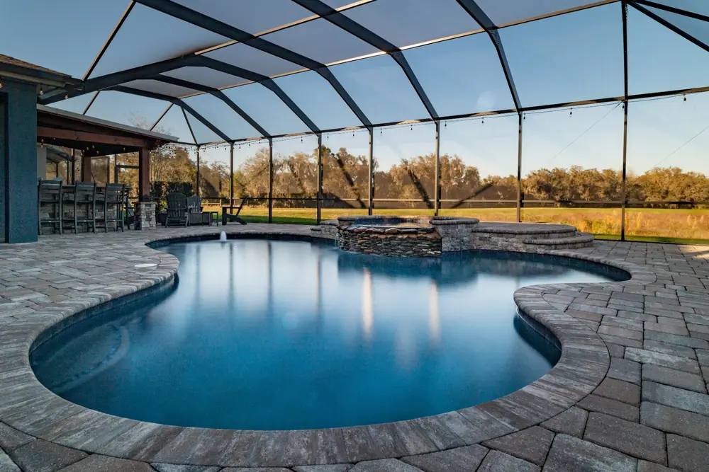 Freeform pool and raised spa before sunset — Backyard Oasis custom pool project by Wahoo Pools in Tampa Bay, FL