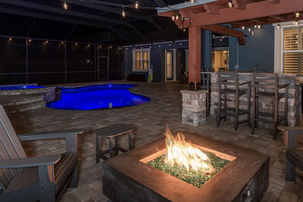 Glowing fire pit at night — Backyard Oasis custom pool project by Wahoo Pools in Tampa Bay, FL