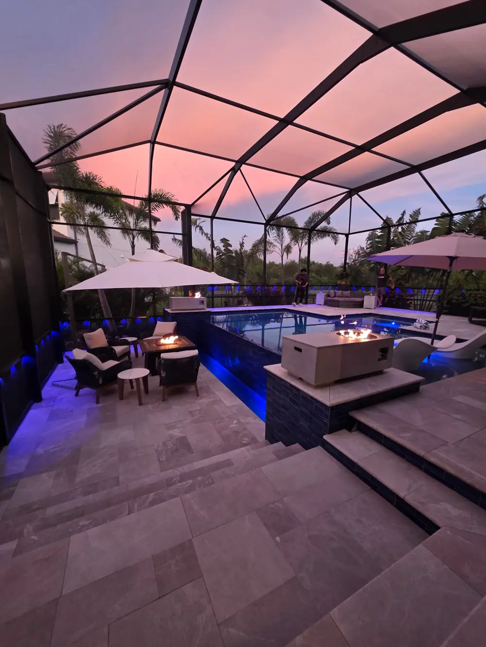 Sunset Lanai Retreat — travertine deck and stacked-tile spa wall at dusk — Wahoo Pools project in Tampa, FL
