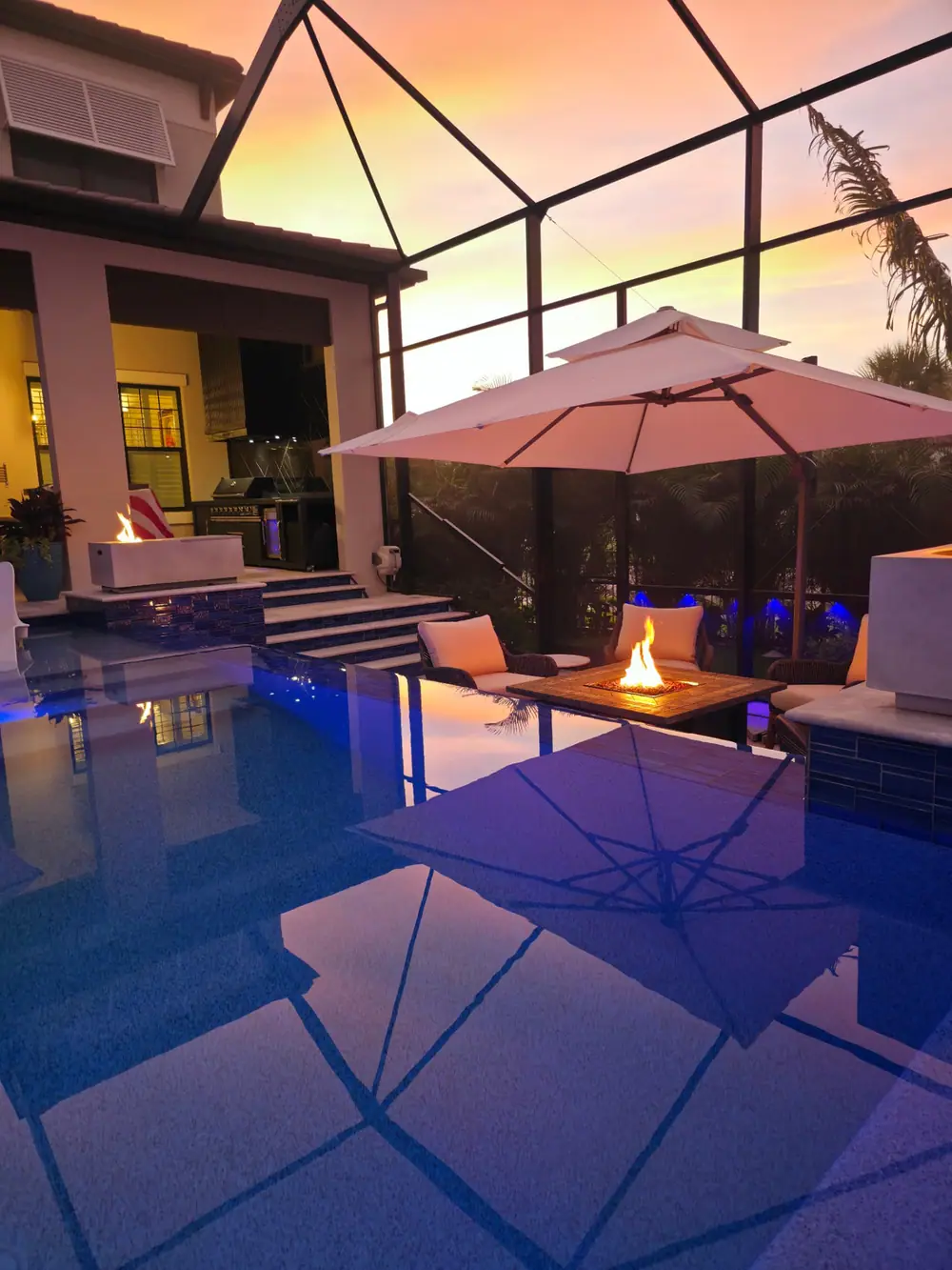 Sunset Lanai Retreat — outdoor kitchen and fire features reflected in the pool — Wahoo Pools project in Tampa, FL