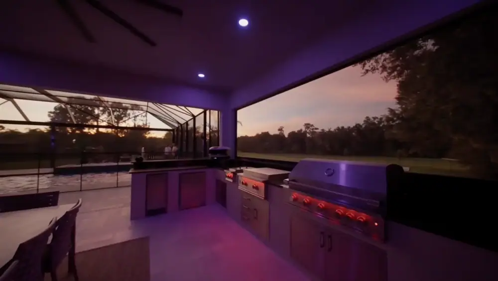 Twilight Lanai Estate — outdoor kitchen with grill and pool view at dusk — Wahoo Pools project in Tampa, FL
