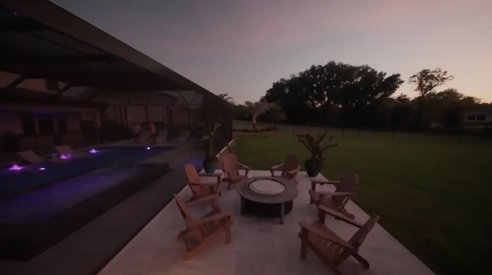 Twilight Lanai Estate — paver fire-pit lounge beside the lit pool at sunset — Wahoo Pools project in Tampa, FL
