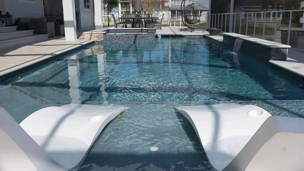 Pool with fire bowls at dusk — Vera Canal Retreat custom pool project by Wahoo Pools in Apollo Beach, FL