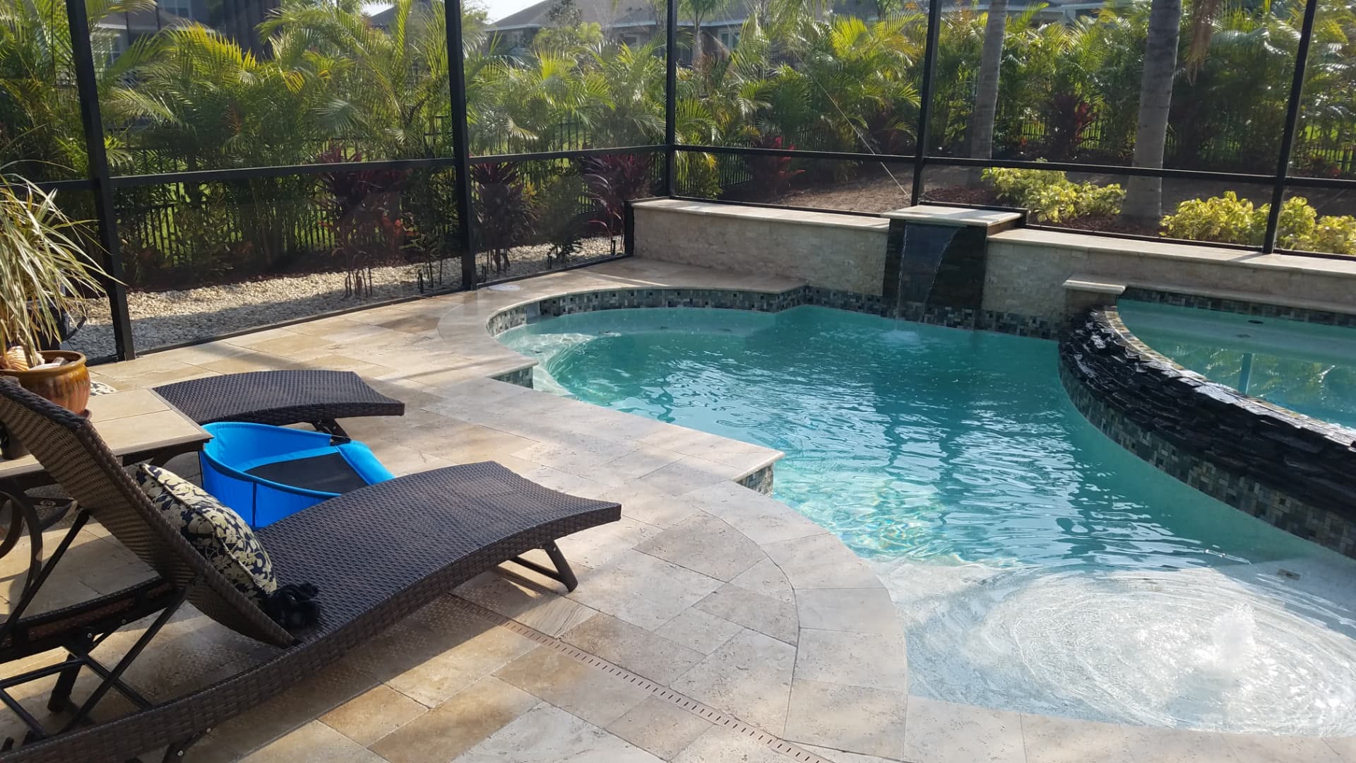 Bubbler sun shelf and curved travertine coping beside the raised spa — Apollo Travertine Spa Retreat, an Apollo Beach, FL pool project by Wahoo Pools